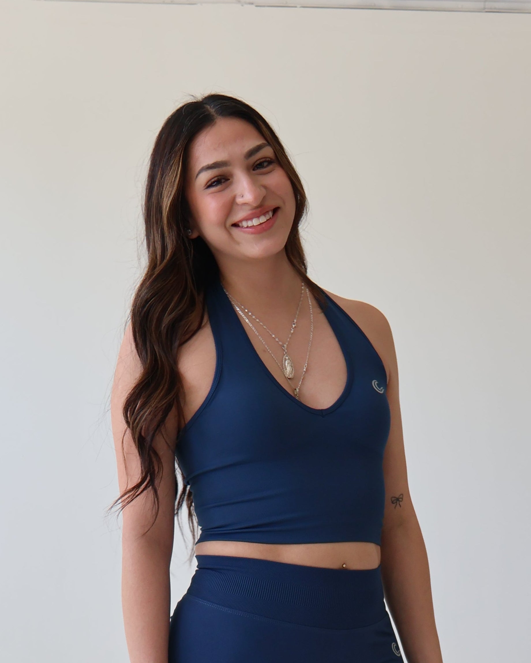 Woman in navy athletic outfit standing against a white wall