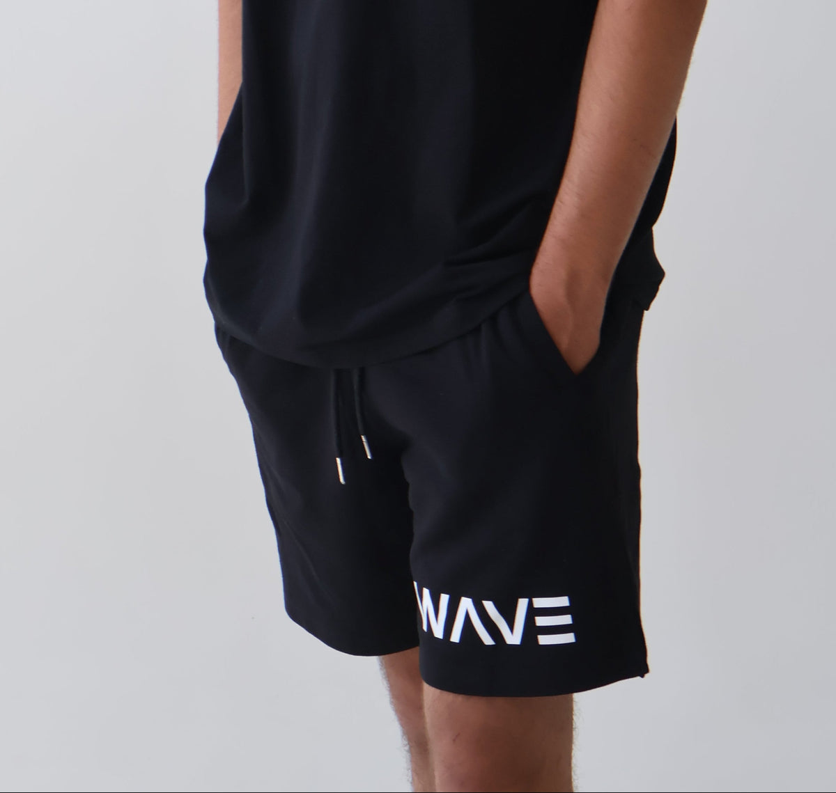 Person wearing a black 'WAVE' t-shirt and shorts on a plain background