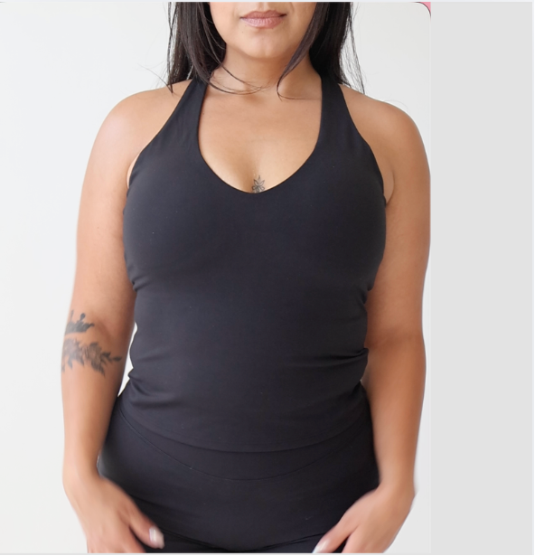 A woman wearing a black halter-neck tank top against a plain light gray background.